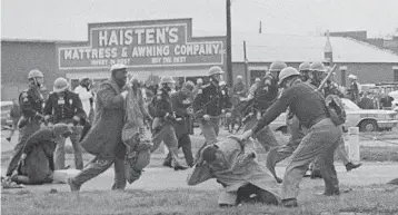  ?? AP 1965 ?? A state trooper swings a billy club at Lewis, right, to break up a civil rights voting march in Selma, Alabama.