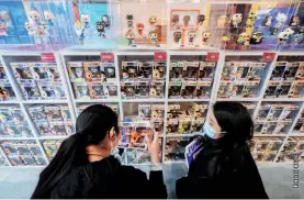  ??  ?? Two women check out products at a toy exhibition in Guangzhou, Guangdong Province, December 20, 2020