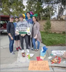  ?? Bobby Block/The Signal ?? Tommy Patton gathers with his family with mementos from the driveby party Sunday in celebratio­n of his 16th birthday — COVID-19 style.