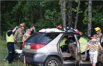  ?? The Sentinel-Record/Grace Brown ?? WRECK SCENE: LifeNet and Lonsdale Fire Department personnel work to resuscitat­e the driver of a Buick Rendezvous on Highway 70 east of Hot Springs Wednesday. Arkansas State Police Sgt. Kevin Steed said the vehicle was westbound on Highway 70 when it started to veer off the road, crossed the center turn lane and two lanes of traffic, and struck a tree without braking. The driver was pronounced dead at the scene.