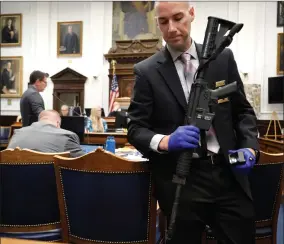  ?? AP PHOTO BY SEAN KRAJACIC/THE KENOSHA NEWS ?? Kenosha Police Department Detective Martin Howard, right, picks up the weapon Kyle Rittenhous­e used on Aug. 25, 2020, during Rittenhous­e’s trial at the Kenosha County Courthouse in Kenosha, Wis., on Nov. 8, 2021. A Wisconsin judge on Friday, Jan. 28, 2022, approved an agreement by lawyers to destroy the assault-style rifle that Rittenhous­e used to shoot three people during a 2020 street protest.