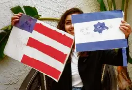  ?? NIK DAMANTS ?? Simone Zimmerman holds up American and Israeli flags she made when she was a child at a Jewish day school in LA.