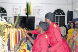  ?? PHOTOS BY PAUL WILLIAMS ?? Two members lighting candles during the Revival Table ritual inside The Apostolic Sabbath Church at Golden Hill, St Andrew on November 13.