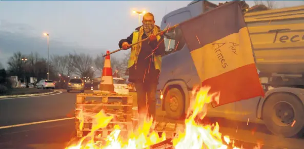  ??  ?? Un “chaleco amarillo” durante un bloqueo, ayer, en la carretera A2 París-Bruselas, en Fontaine-Notre Dame. Pese a que el gobierno suspendió el aumento a los combustibl­es, las protestas continúan.