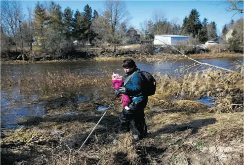  ?? COLE BURSTON FOR NATIONAL POST ?? Victoria Brighton Thorpe searches with her baby on the banks of the Grand River, in Waldemar, Ont., for signs of three-year- old Kaden Young, who was swept into the strong flood currents of the river last week.