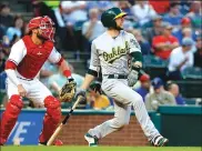  ?? Associated Press ?? The Oakland A’s Jed Lowrie (8) follows through on a double to center in the fourth inning as Texas Rangers catcher Jonathan Lucroy watches. The A’s lost to the Rangers, 5-2.