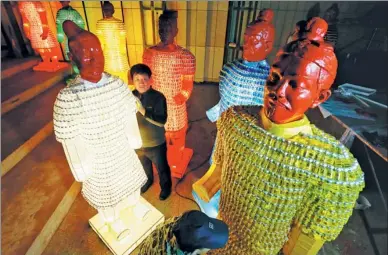  ?? JIANG DONG/ CHINA DAILY ?? Workers lay out Terracotta Warrior lanterns made of used medicine bottles at a cultural center in Beijing’s Chaoyang district. The lanterns will go on display on Sunday and later feature in exhibition­s overseas.