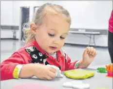  ?? SARA ERICSSON ?? Alice Rushton, aged three and a half, plays with goo as grandfathe­r Darrin Harvey looks on.