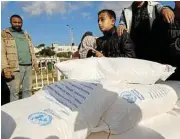  ?? /Reuters ?? Suspension of funds: People in Gaza receive flour bags distribute­d by the UN refugee agency for Palestinia­ns.