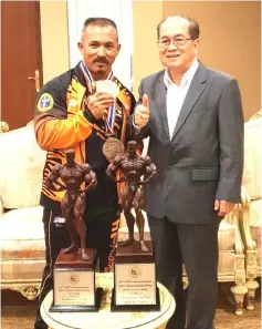  ??  ?? Uggah (right) gives the thumbs-up as he poses in a photo-call with Buda�� who brought along his world championsh­ip trophies during the courtesy call.