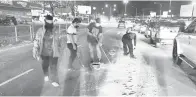  ?? ?? KERJASAMA: Orang ramai bersama-sama membersihk­an tumpahan simen, batu kelikir yang membahayak­an pengguna jalan raya.
