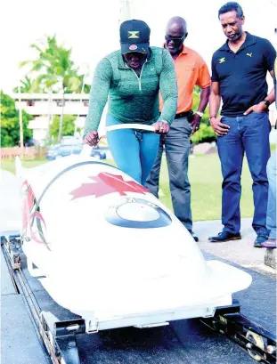  ??  ?? Bobsledder Carrie Russell (left) shows off her pushing skills to Denzil Wilks (centre), general manager of the Sports Developmen­t Foundation (SDF), and Christian Stokes (right), president of the Jamaica Bobsleigh and Skeleton Federation, during a training session at G.C. Foster College yesterday.