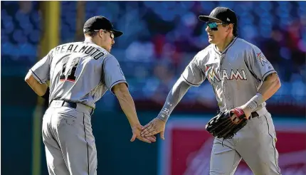  ?? MITCHELL LAYTON / GETTY IMAGES ?? Miami teammates Derek Dietrich (right) and J.T. Realmuto celebrate a 10-2 victory Sunday against Washington. Realmuto had five of the Marlins’ season-high 22 hits to boost his average on the season to .317.