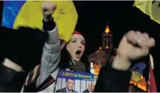  ?? VIKTOR DRACHEV/ AFP/GETTY IMAGES ?? A protester holds a placard showing Ukrainian President Viktor Yanukovych, left, and Prime Minister Mykola Azarov behind bars at a rally Wednesday.