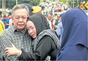  ?? AFP ?? The parents of one of the victims of the fire stand outside Darul Quran Ittifaqiya­h school yesterday.