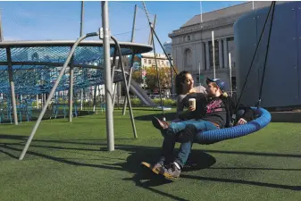  ??  ?? Jessie Cooper and Justin Roth embrace on a swing at Civic Center, where new playground­s have added to the effort to make the place appealing and family-friendly.