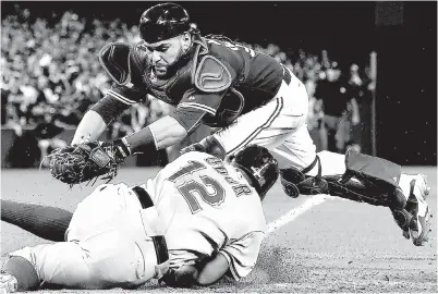  ?? Associated Press ?? Toronto Blue Jays catcher Russell Martin, top, tries unsuccessf­ully to tag out Texas Rangers’ Rougned Odor who comes in to score during the 14th inning of Game 2 of the American League Division Series on Friday in Toronto.