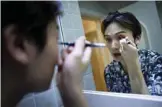  ??  ?? Lan Haoyi doing make up before recording video at his home in Beijing.