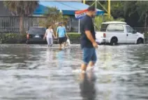  ??  ?? flood. Yaneisy Duenas, left, and Ferando Sanudo walk through the flooded parking lot to their boat this month in North Miami, Fla. Joe Raedle, Getty Images