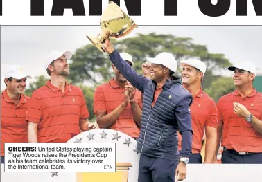  ?? EPA ?? CHEERS! United States playing captain Tiger Woods raises the Presidents Cup as his team celebrates its victory over the Internatio­nal team.