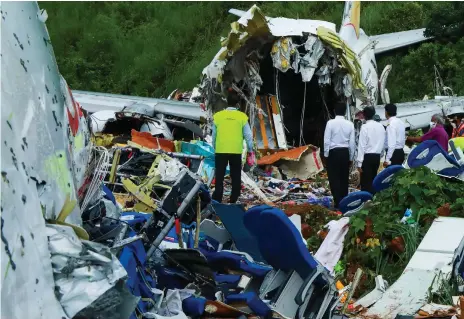  ?? AFP ?? Aviation officials inspect the wreckage of an Air India Express jet that crashed at Kozhikode Airport in Kerala after flying from Dubai. Eighteen people, including both pilots, were killed when the plane overshot the runway in bad weather and plunged into a gorge
