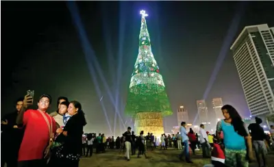  ?? — AP ?? A Sri Lankan family takes photograph­s standing near an enormous artificial Christmas tree as others gather around it in Colombo, Sri Lanka, Saturday.