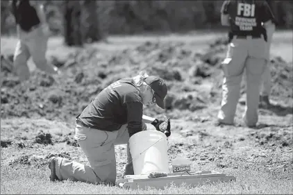  ?? Staff photo by Evan Lewis ?? A member of the FBI Evidence Response Team cleans an article of interest that was unearthed Thursday while searching the grounds where a house once stood off Nelson Street in New Boston, Texas. They were searching for the body of La Dana Renee Newton...