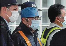 ??  ?? Kaum erkennbar: Carlos Ghosn (Mitte) verlässt die Haftanstal­t in Tokio. Er trägt dabei eine weiße Maske bis dicht unter die Augen. (FOTO: AFP)