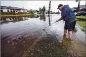  ?? BRETT COOMER — HOUSTON CHRONICLE ?? Chris Hendricks tries to clear debris from a storm drain to help with the draining of floodwater­s on his street in Galveston, Texas, on Tuesday.