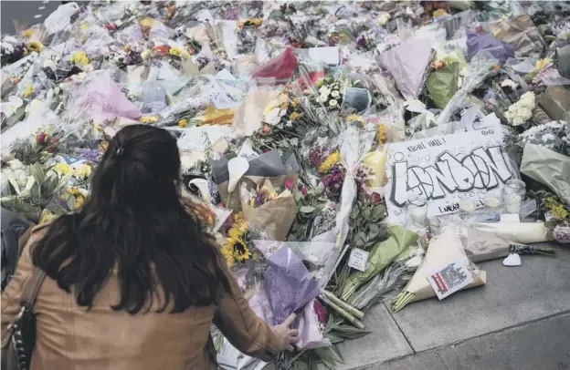  ??  ?? A woman lays flowers near the scene of last Saturday’s terrorist attack on London Bridge, where eight people were killed and at least 48 injured.