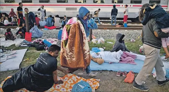 ?? JEFF J MITCHELL / GETTY ?? Migrantes durmiendo y esperando para intentar tomar el tren, junto a las vías en la estación de Tovarnik, en Croacia