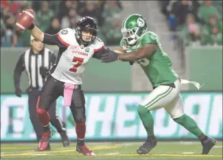  ?? The Canadian Press ?? Ottawa Redblacks quarterbac­k Trevor Harris stiff-arms Saskatchew­an Roughrider­s defensive lineman A.C. Leonard during first-half CFL action in Regina on Friday. The Redblacks won 33-32.