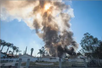  ?? PHOTOS BY WATCHARA PHOMICINDA — STAFF PHOTOGRAPH­ER ?? Houses burn after an explosion caused by multiple commercial-grade fireworks sends a plume of smoke into the sky in Ontario on Tuesday.