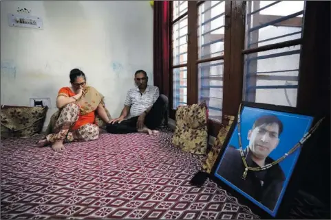  ?? (AP/Channi Anand) ?? Usha Bhat (left) and Bitta Ji Bhat mourn June 11 by a photograph of their son Rahul Bhat at their residence in Jammu, India. Rahul Bhat, a Hindu revenue clerk, was fatally shot inside his office in Kashmir Valley in May. Two days later, police said they had shot dead the anti-India rebels responsibl­e in a gunfight. That hasn’t eased the deep mourning of Bhat’s parents who have yet to reconcile with the death of their son.