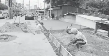  ?? (PNA / File photo) ?? A constructi­on worker is seen preparing to cement a sidewalk along a highway in Dasmariñas City, Cavite. A lawmaker has proposed to give special breaks to workers during times of intense heat.