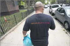  ?? MARK LENNIHAN - THE ASSOCIATED PRESS ?? Driver Frank Robinson delivers prepackage­d meals Tuesday, July 7, in New York. Robinson is one of 200 drivers paid by catering startup HUNGRY to deliver prepackage­d meals to stay-at-home elderly and low-income kids.
