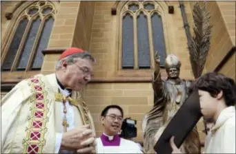 ?? ROB GRIFFITH — THE ASSOCIATED PRESS FILE ?? In this file photo, Cardinal George Pell, left, reads a bible during the blessing of a statue of John Paul ll at St. Mary’s Cathedral in Sydney, Australia. Australian police say they are charging Pell with historical sexual assault offenses.