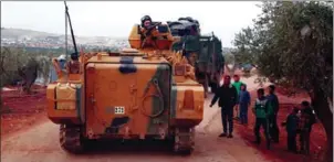  ?? NAZEER AL-KHATIB/AFP ?? A Turkish armoured personnel carrier drives past Syrian boys near the border crossing between Syria and Turkey, in the north of Aleppo province, on Sunday.