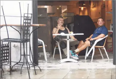  ?? Tyler Sizemore / Hearst Connecticu­t Media ?? Mike Picciallo, left, and Phil Malia take cover from the rain inside Bari 167 Italian Restaurant as Tropical Storm Henri hits Stamford on Sunday.