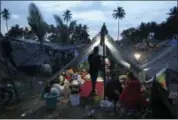  ?? TATAN SYUFLANA — THE ASSOCIATED PRESS ?? Villagers gather at a temporary shelter after fleeing their damaged village affected by Sunday’s earthquake in North Lombok, Indonesia, Wednesday. Aid has begun reaching isolated areas of the Indonesian island struggling after an earthquake killed over 100 people as rescuers intensify efforts to find those buried in rubble.