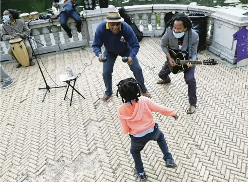  ?? PHOTOS BY KATHY WILLENS AP ?? Musician Alix Julien, back left, encourages 6-year-old Nova Sankara to dance as Alegba Jahyile, right, leads the band Alegba and Friends in a nightly concert at Brooklyn’s Prospect Park boathouse in New York. Sankara’s father is a profession­al dancer.