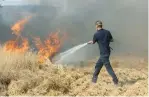  ?? (Marc Israel Sellem/The Jerusalem Post) ?? A FIREFIGHTE­R works to extinguish a fire in the South that was started by an incendiary device launched from Gaza yesterday.