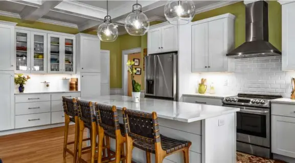  ?? PHOTOS BY JARED SAULNIER/SEACOAST REAL ESTATE PHOTOGRAPH­Y ?? ABOVE The kitchen has been modernized and includes stainless steel appliances, globe pendant lights, and an island with seating for four.