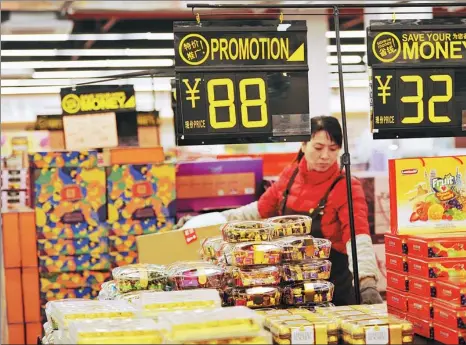  ?? YU FANGPING / XINHUA ?? A saleswoman arranges imported snacks at a duty-free store in Qingdao, Shandong province.