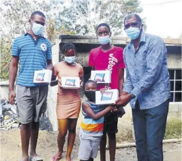  ??  ?? Councillor for the Springmoun­t Division of the St James Municipal Corporatio­n Urval Gordon (right) presents tablets to students who lost their devices in a fire that razed a house in which they were attending online classes in John’s Hall last week.