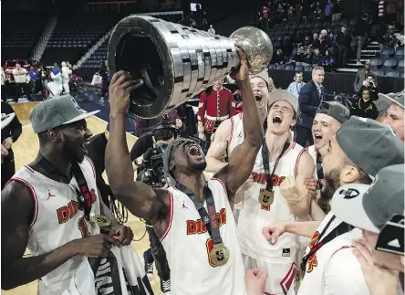  ?? DARREN CALABRESE/THE CANADIAN PRESS ?? Members of the Calgary Dinos hoist up the W.P. McGee Trophy after defeating the Ryerson Rams 79-77 Sunday in Halifax to win their first U Sports men’s basketball title.