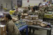  ?? TONY DEJAK ?? FILE - In this March 24, 2020, file photo, members of The Ohio National Guard assist in repackagin­g emergency food boxes for food distributi­on at the Cleveland Food Bank in Cleveland. The use of National Guard units around the country to help with the response to the coronaviru­s pandemic is prompting rumors of a national lockdown or even martial law. Guard units are now helping to transport medical supplies, distribute food and even help direct traffic at drive-through testing sites.