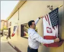 ?? MARK MIRKO/HARTFORD COURANT ?? Attorney Adrian Baron hangs a Polish American flag outside his law office on Broad Street in New Britain’s Little Poland section.