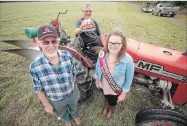  ?? JASON BAIN EXAMINER ?? Volunteer Warren Craft displays his hat with buttons fromIntern­ational Plowing Matches from 2002 to 2017 while sitting on his Massey 245 tractor, flanked by Peterborou­gh County Plowman's Associatio­n president Roy Craft and Queen of the Furrow Ashley Buck.