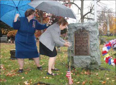  ?? LAUREN HALLIGAN - MEDIANEWS GROUP ?? Anne Farley, New York state president of the Daughters of the 1812, holds an umbrella for Anne Davis, Honorary Vice President National and New York State Chairperso­n for Grave Markers for the Daughters of 1812during a ceremony at Samuel “Uncle Sam” Wilson’s gravesite at Oakwood Cemetery in Troy.